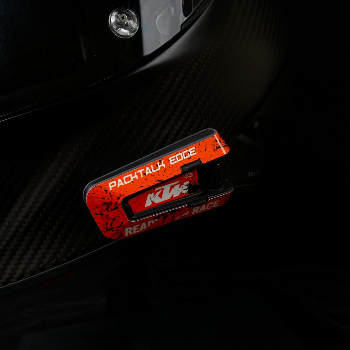 Orange racing-style decal shown on a helmet-mounted PACKTALK EDGE communicator.